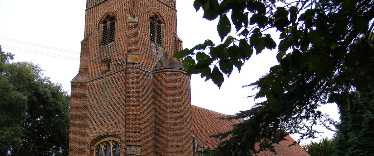 A historic brick church with a tall tower and arched windows.