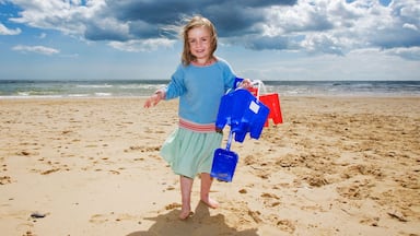 Young girl holding bucket and spade on beach, Walberswick, Suffolk, England, UK