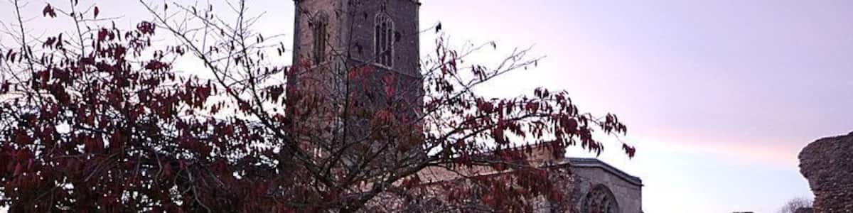 Eine Kirche mit hohem Turm und einer Steinmauer mit Grabsteinen.
