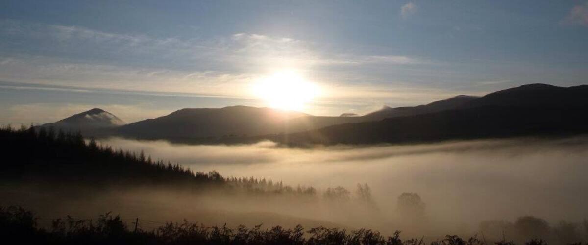 A sunrise over a mountain range with mist.