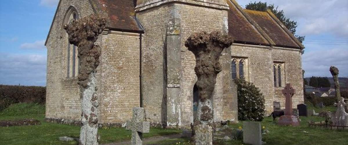 An old church with a bell tower and a graveyard in front.