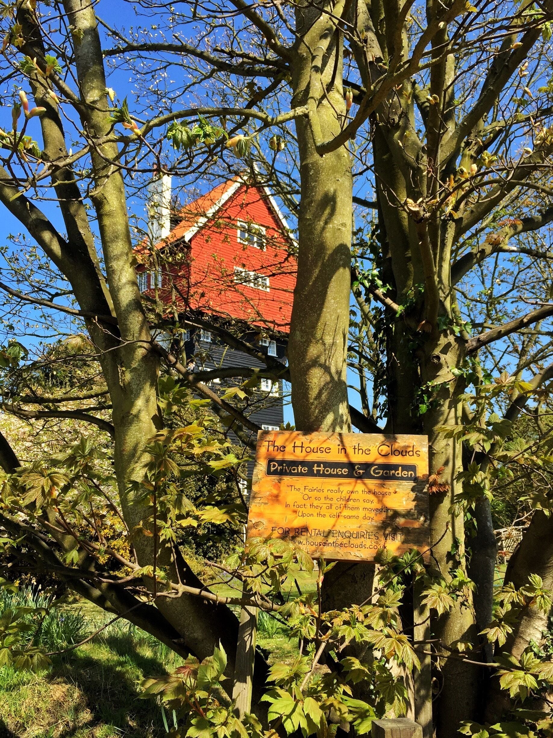 A red house with a sign in front stating it's a private house and garden.