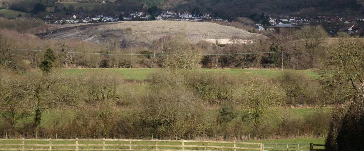 A rural landscape with a village, rolling hills, and a clear sky.