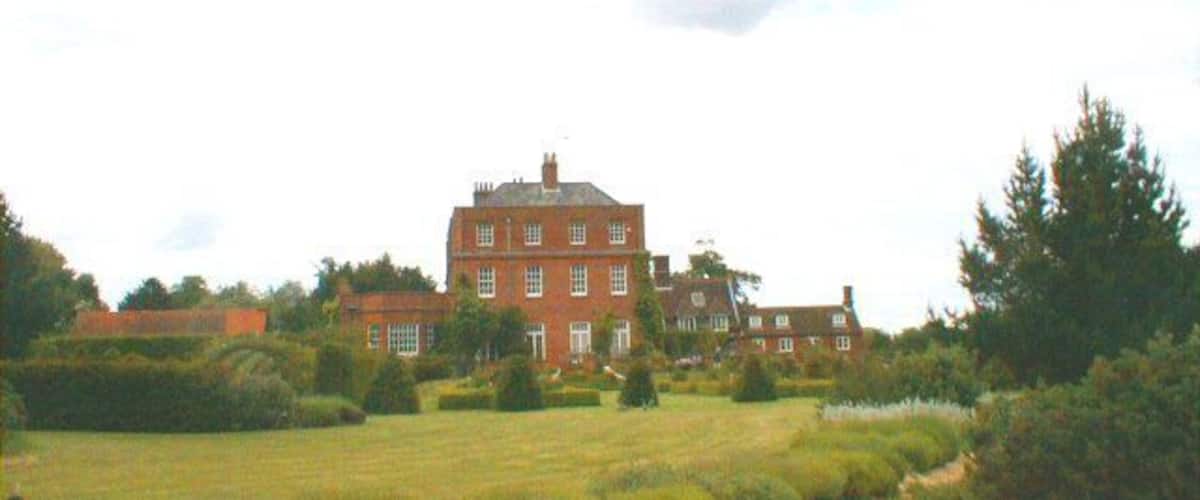 A large red brick building with multiple windows and a well-maintained lawn in the foreground.