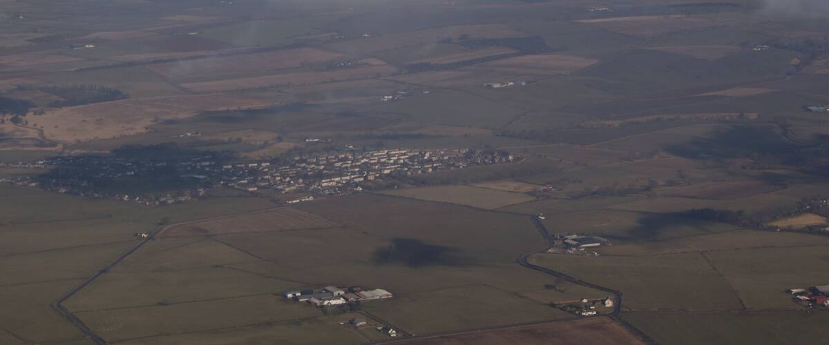 An aerial view of a rural landscape with fields, a small town, and a large cloud formation.