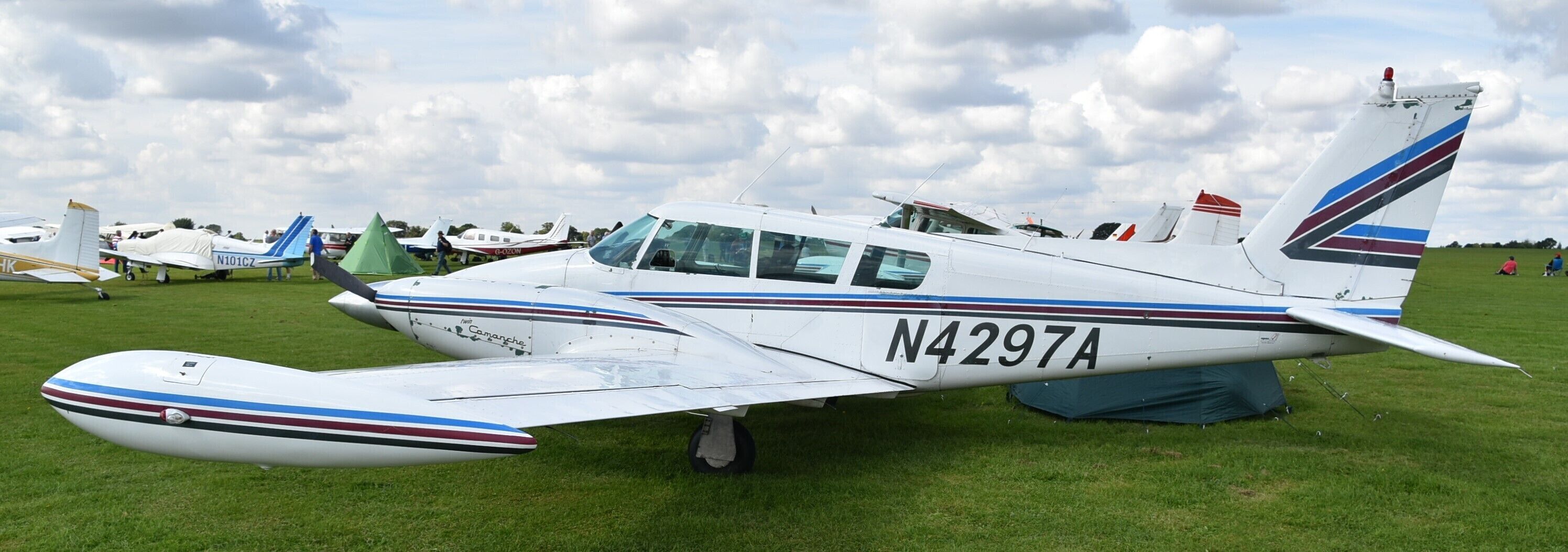 A small white aircraft with registration N4297A parked on a grassy field.