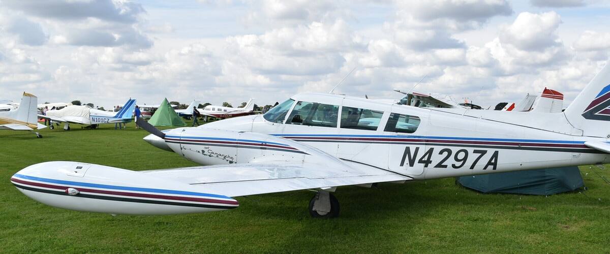 A small white aircraft with registration N4297A parked on a grassy field.