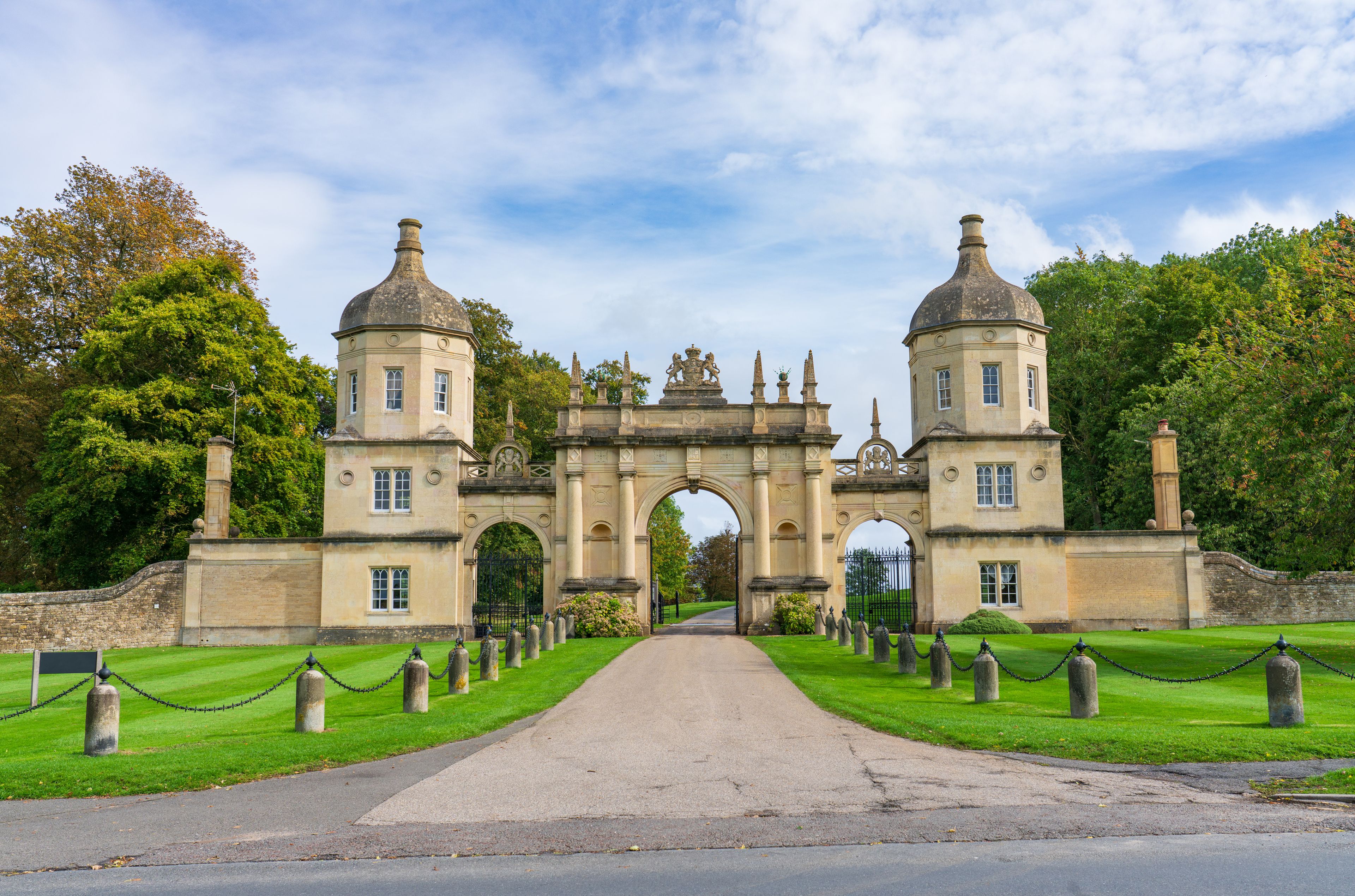 A historic gatehouse with two towers, an archway, and a pathway lined with headstones.