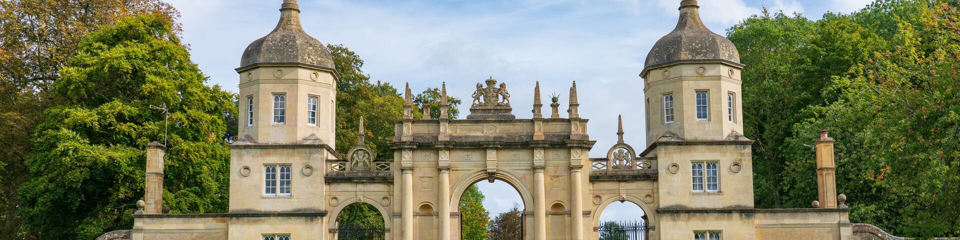 A historic gatehouse with two towers, an archway, and a pathway lined with headstones.