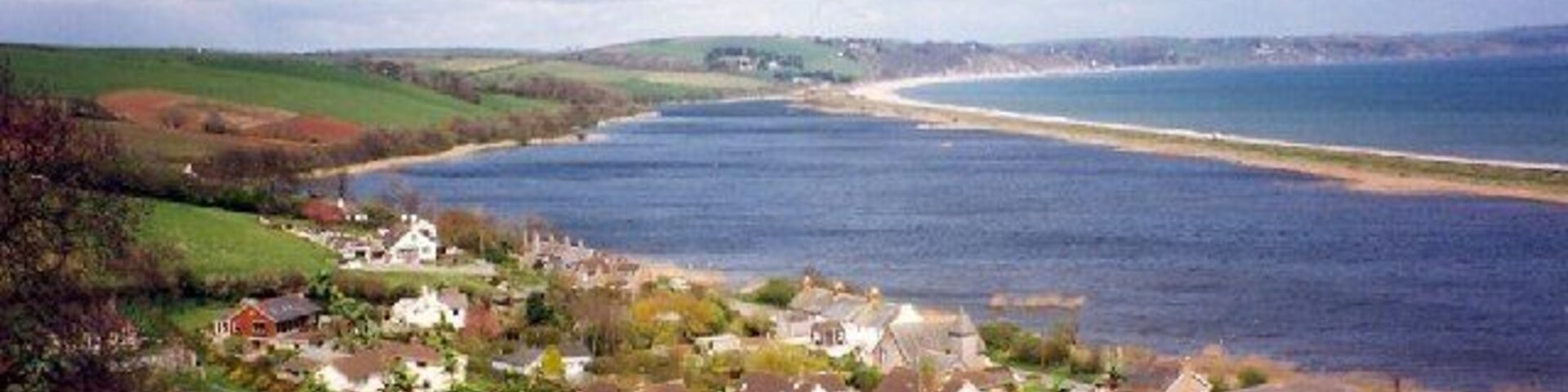 Un pueblo costero con casas, una playa y vistas al mar.