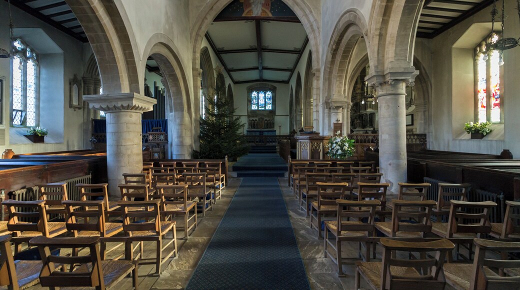 The north arcade is said to date from around 1066 thus it would seem that the church was originally a small Norman church of which only the Nave and Tower remain. The walls and windows of the North and south aisles of the nave date from the Restoration in 1846. Sometime in the 14th century the chancel arch was built, but the chancel it led to has gone. The arch leading to the tower was built about the same time and probably it was then that the nave walls were heightened and a clerestory provided. In 1846 the roof of the chancel was lowered and a low lath and plaster arch constructed under the chancel arch that now exists. This was removed in 1935 and the old arch – sadly hacked about – was revealed. It was impossible to raise the chancel roof, so the space in the apex of the arch was filled by a painting: “Our Lord in Glory”, by Miss Jessie Bayes. In the 15th century, all that now exists beyond the chancel arch and beyond the eastern arches of the nave aisles – was entirely rebuilt. The Turnor chapel is in the north aisle and was built in 1448 by Henry Rochford (The last of that name to live here. He probably built the south aisle rather later). There is a large black and white monument to Sir Edmund Turnor (1619-1707) the founder of the present family of Turnors of Stoke Rochford. Other Turnor memorials are also here. On the floor in the chapel are two medieval monuments. One is the recumbent figure of a knight in armour, and his lady, with a curious covering over them. Probably this monument was in the North stoke church, and after that church was abandoned and ceased to exist, was, after many years exposure in the open, brought here in the 19th century and placed in the middle of the marble floor. No one knows whom the figures represent, though 100 years ago it was thought to be a Neville monument and that name was cut on the surrounding stone work. Bishop Hine believes the arms on the shield to be Cantelupe. The other monument in the North Wall; it is a tomb in a canopied recess, with angels bearing shields, all however, blank today. Nothing is known of this monument. In the south aisle there is the Cholmeley chapel. The most striking object is the large monument erected in 1641 to the memory of Sir Henry Cholmeley (d 1632) the first of the family which still lies at Easton Hall in the parish. The family memorials extend down the south wall including a war memorial to all the Cholmeleys who died in the Great War. Beneath the carpet in the chancel are the Rochford brasses. The Rochfords held Stoke for most of the 15th century. One brass is Henry Rochford, the last of the name, in full armour, who died in 1470. He was the builder of the chapels. The other are his wife with her later husband, Oliver St John. An inscription records that Oliver St John’s mother married eventually the Duke of Somerset, and (through her famous daughter Lady Margaret Beaufort) became grandmother of King Henry VII. The reredos dated 1911 was designed by Mrs G F Watts. The figures represent (from left) St Hugh of Lincoln, St Gilbert of Sempringham, and the Blessed Virgin Mary. Those on the right are St John, Bishop King of Lincoln and St Christopher. The font is probably 1846 but the cover designed and given by Mr C H Turnor was placed here in 1937. It follows in feeling the Jacobean work of the 17th century. The stone work of the tower has deeply recessed windows with a Norman string course beneath the belfry windows. The balusters in these windows, one with a criss-cross early date – possible Saxon – and Transitional Norman. The battlemented top and the west window were doubtless added in the 15th century. (From guide book.)