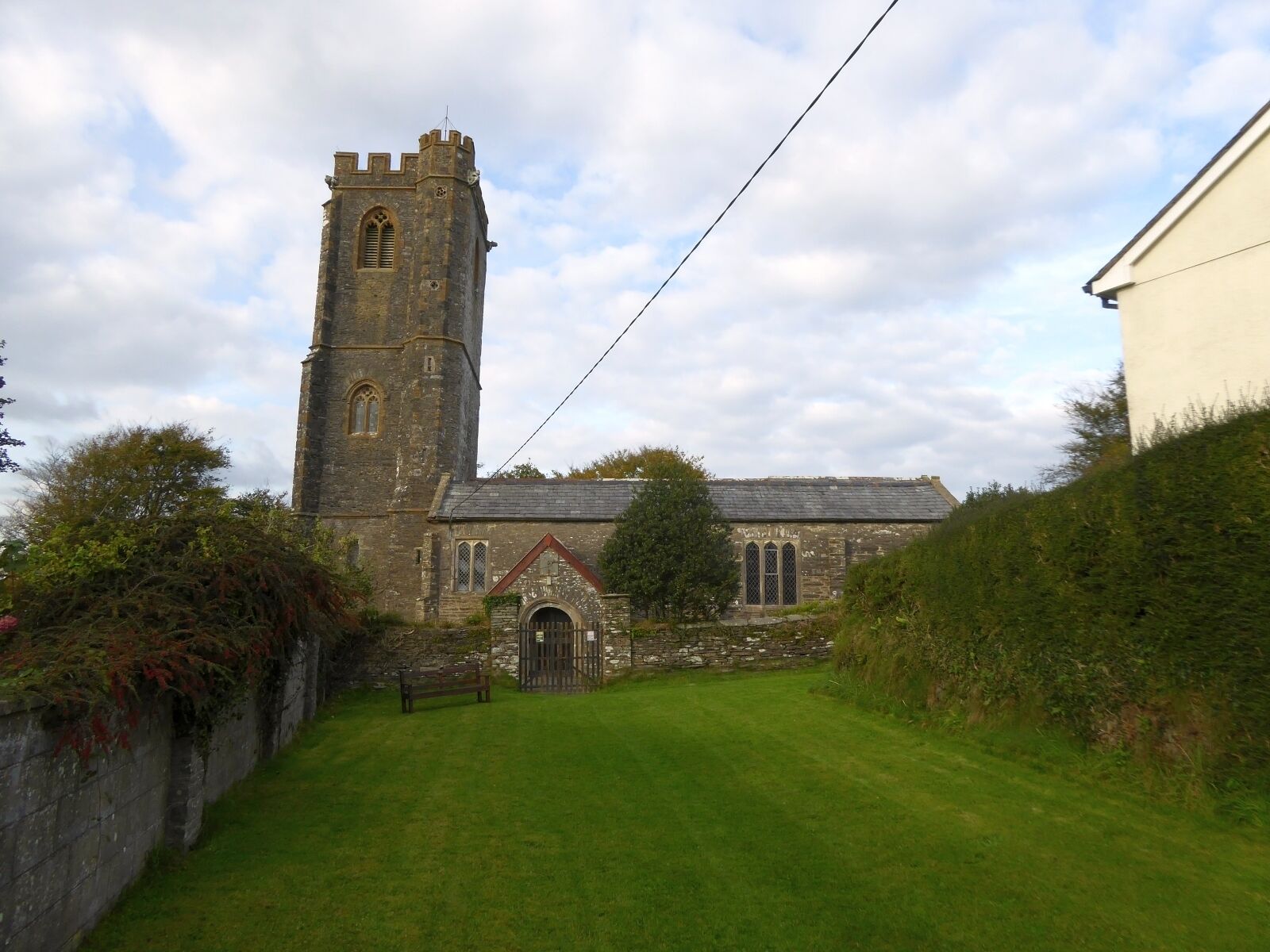 A church with a tall tower and a smaller building with a sloped roof.