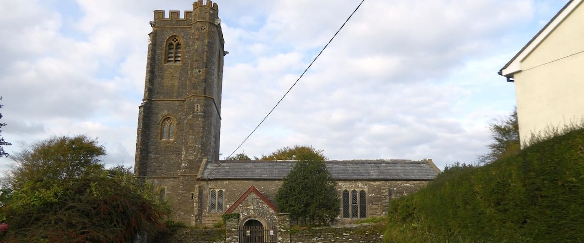 A church with a tall tower and a smaller building with a sloped roof.