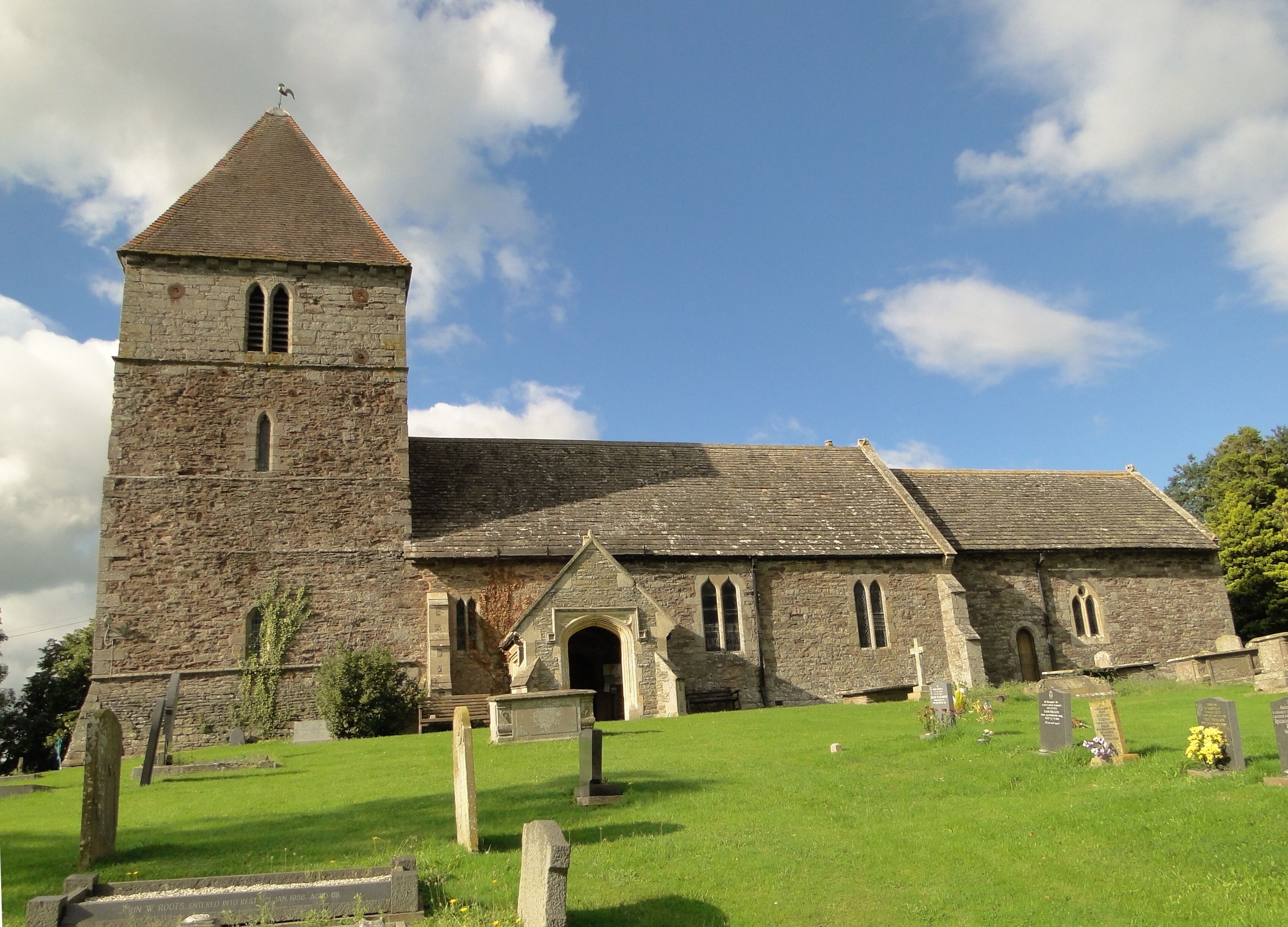 A stone church with a bell tower and a cemetery in front.