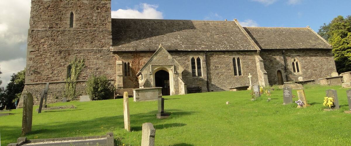 A stone church with a bell tower and a cemetery in front.