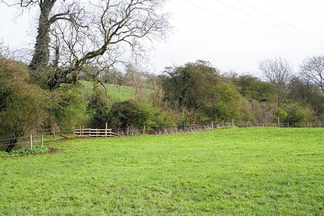 Farmland between Eastwell and Eaton The footpath marker can be seen by the hedgerow that follows a small brook, the River Devon that feeds into Knipton Reservoir and eventually flows into the River Trent.
