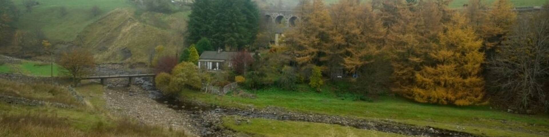 Valley at Heatherycleugh. Heathery Bridge over the Killhope Burn can be seen below 213081 while up above, three of the five arches of the Heatherycleugh road bridge 1506750 are visible in the trees. The village of Lanehead is above to the left.
