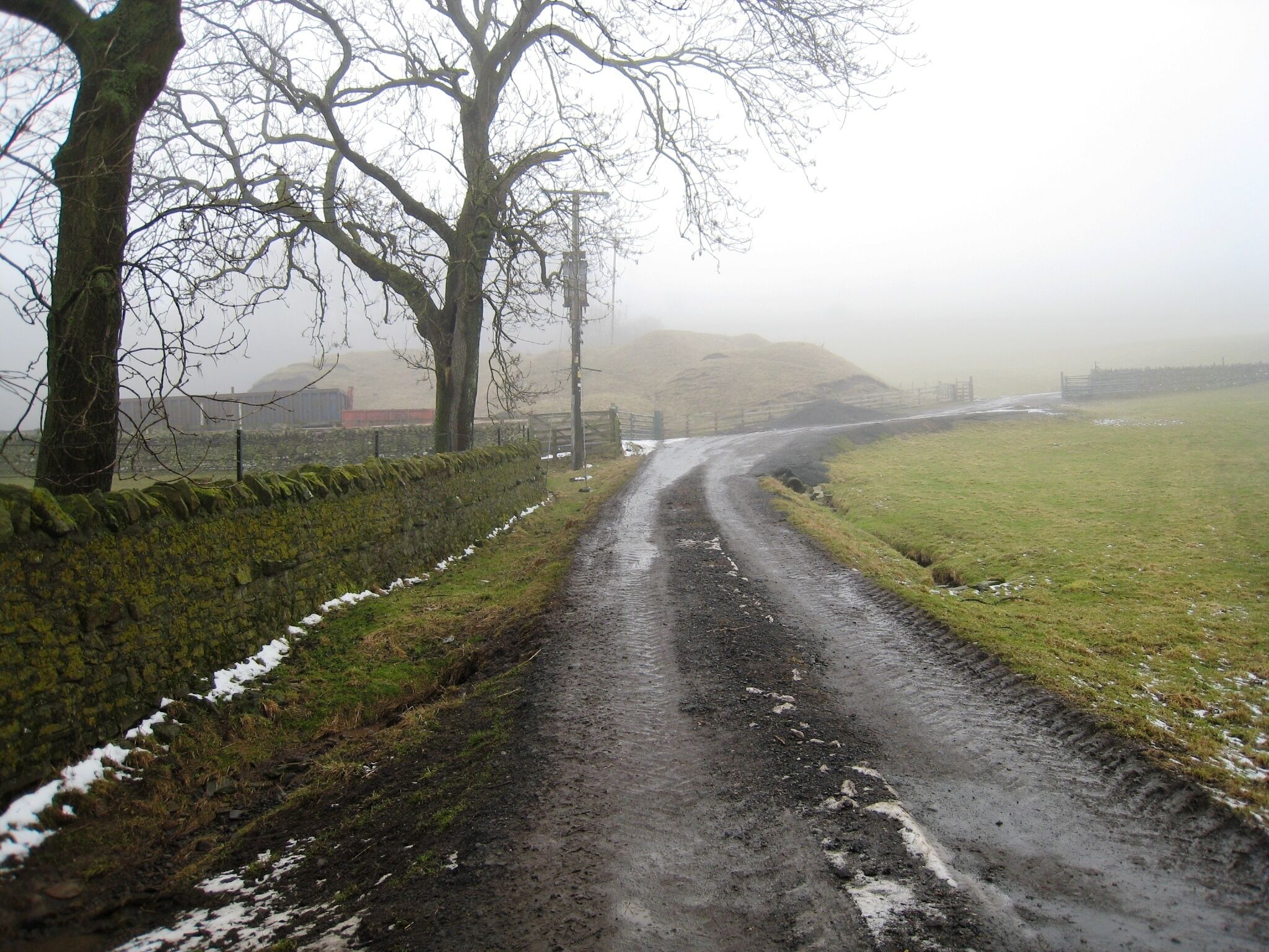 Public footpath to High Barn This photograph shows a view of the public footpath (initially a track) that goes to High Barn and then on to Intake Farm where it terminates. The track shown in the foreground of the picture leads to a disused quarry, the entrance to which can just be seen on the left - beyond the electricity pole. The picture was taken under misty conditions looking in a north-north-westerly direction towards High Barn.