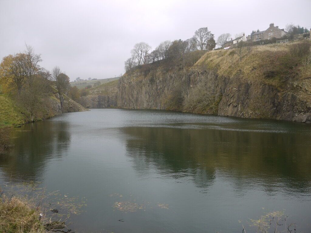 A calm river with a rocky bank and sparse vegetation.
