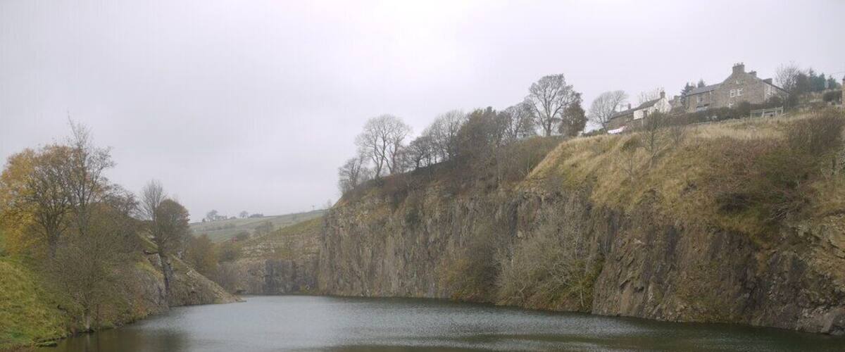 A calm river with a rocky bank and sparse vegetation.