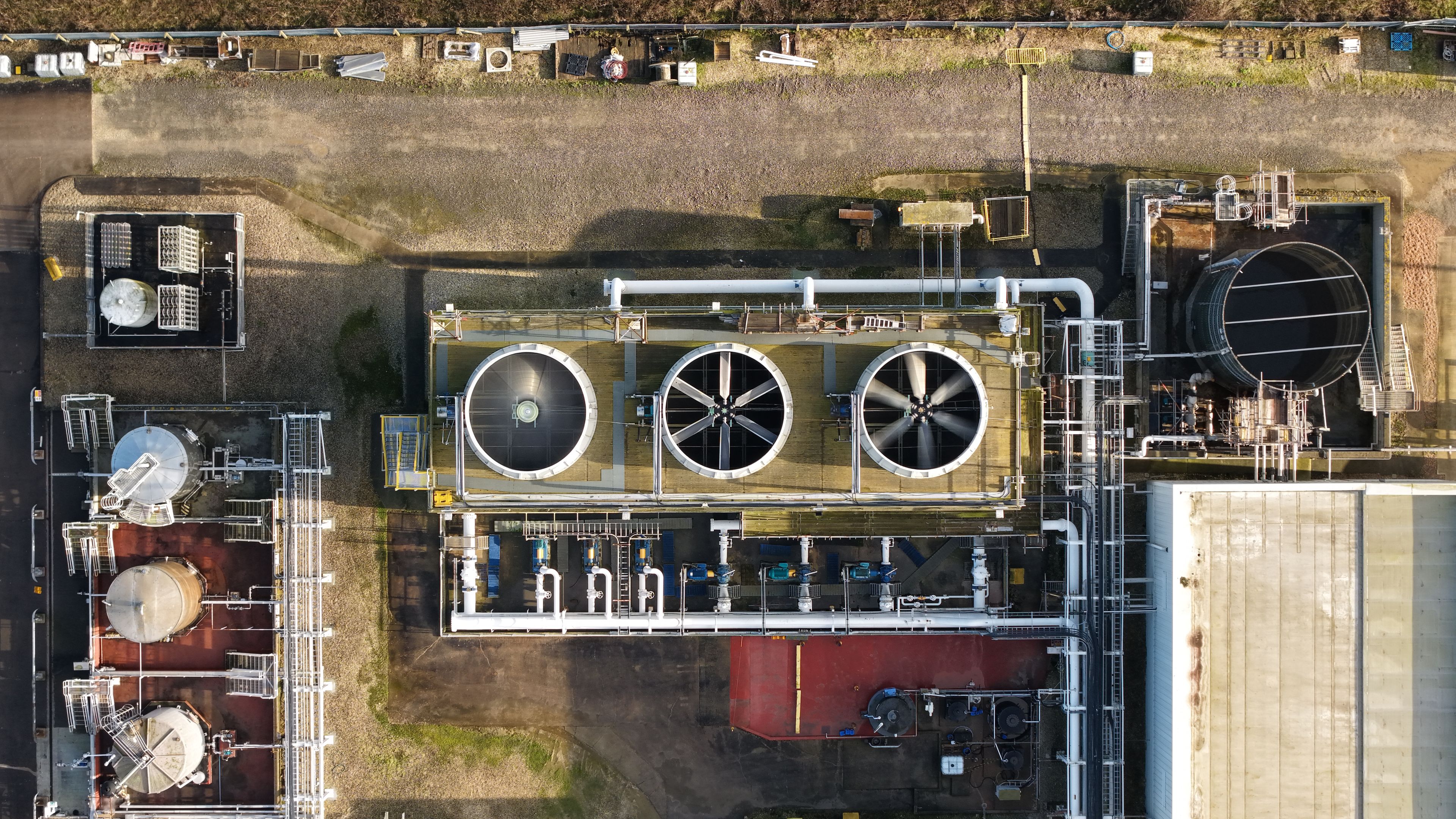 An industrial facility with large cylindrical structures, storage tanks, and complex piping systems.