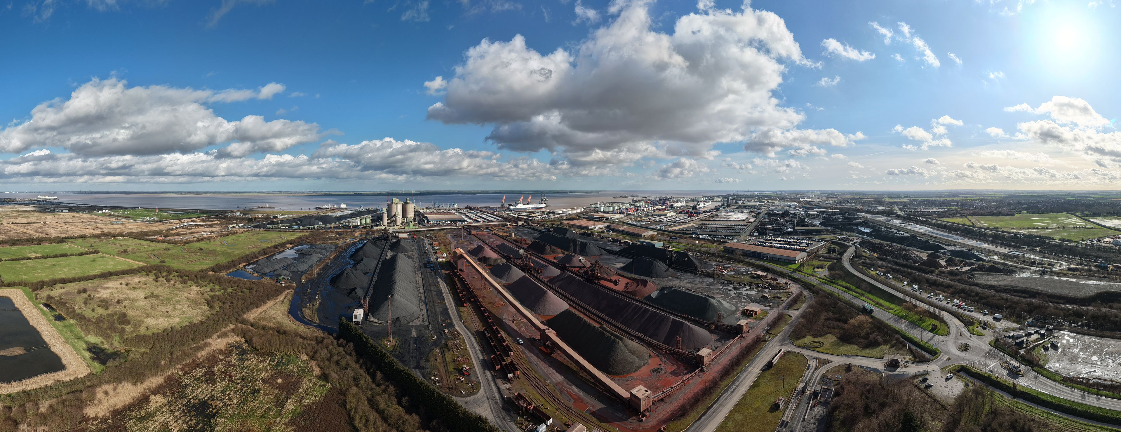 An industrial complex with multiple storage silos, a large ship, and a railway line.