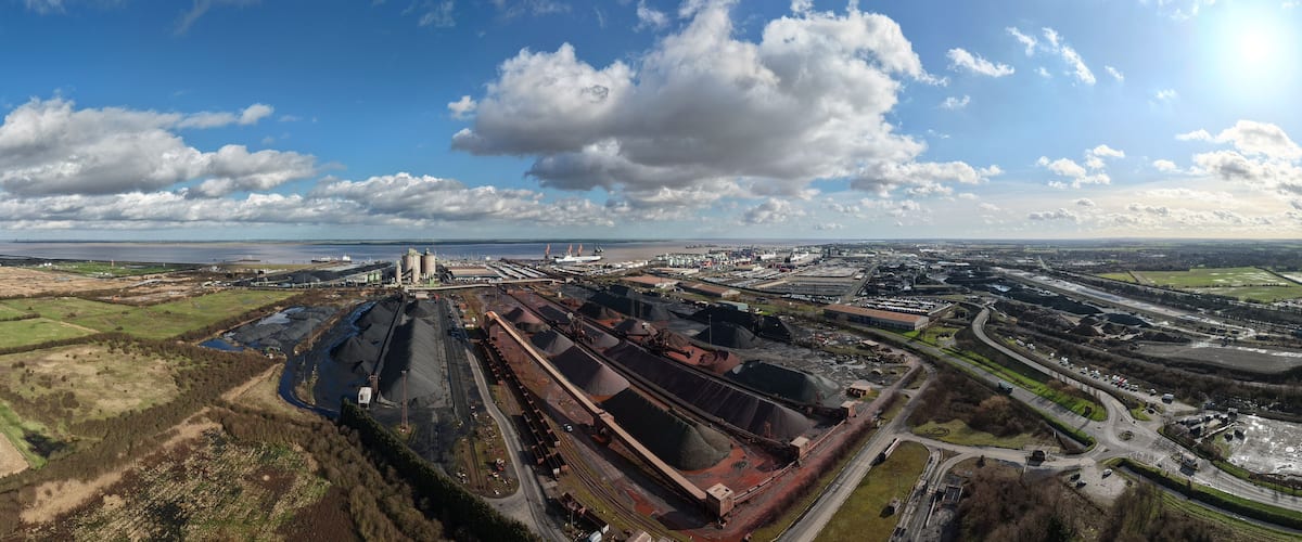 An industrial complex with multiple storage silos, a large ship, and a railway line.