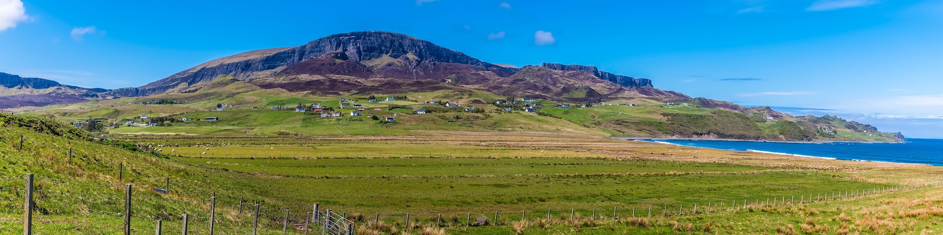 A view from Staffin Bay towards the Quiraing Mountains in the distance on the Isle of Skye, Scotland on a summers day
