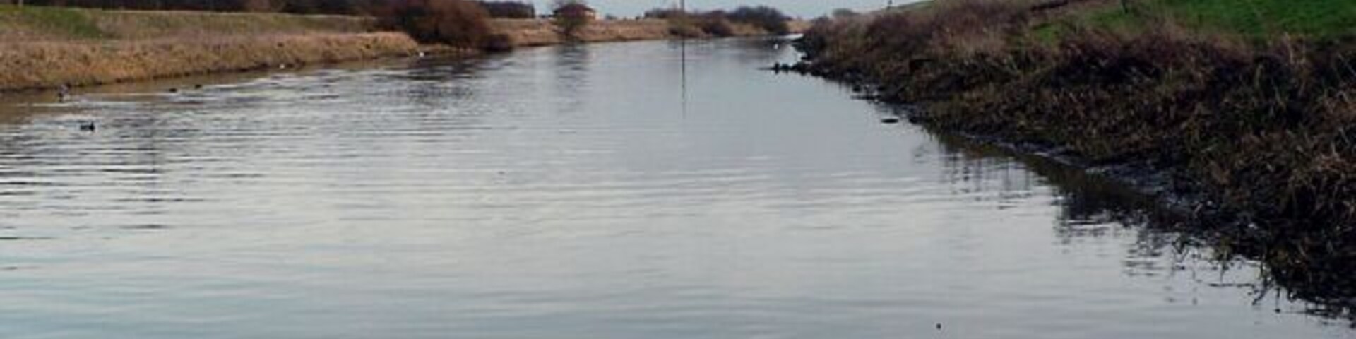 River Witham. Looking southeast from the White Horse jetty. The line of the dismantled railway follows the top of the northern embankment.