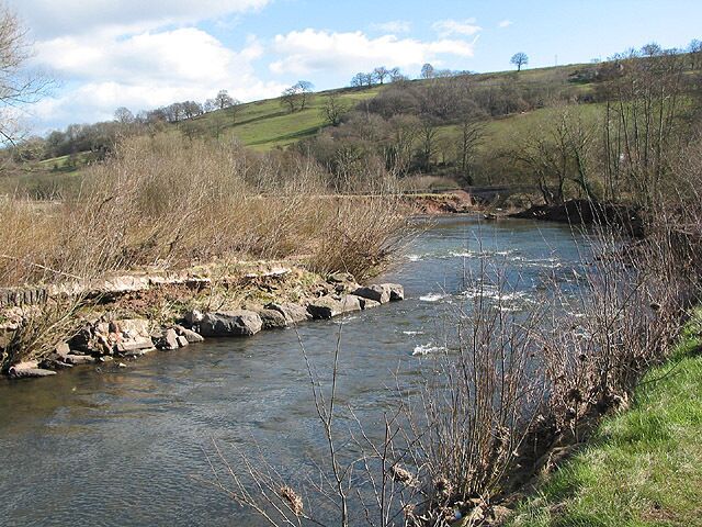 River Monnow flows down towards Skenfrith Bridge Passing over a short stretch of rapids beside the nearby castle. The Monnow flows down through Grosmont and Skenfrith and is one of the larger tributaries of the Wye. It rises in the upland areas of the Black Mountains but for much of its length, it flows through a gentle, fertile valley.