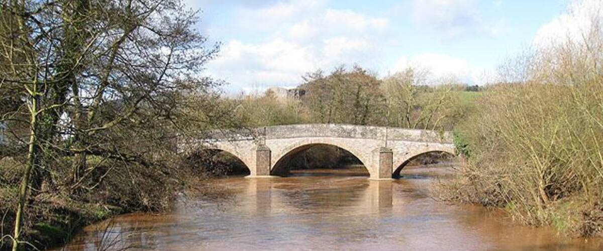 A stone bridge over a river with muddy water.