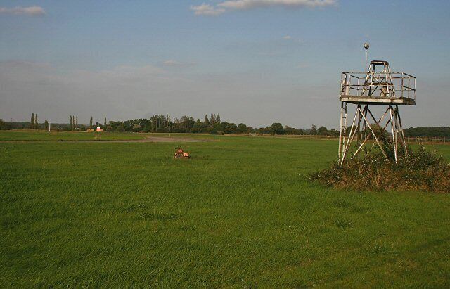 A green field with a metal structure and a red tractor.