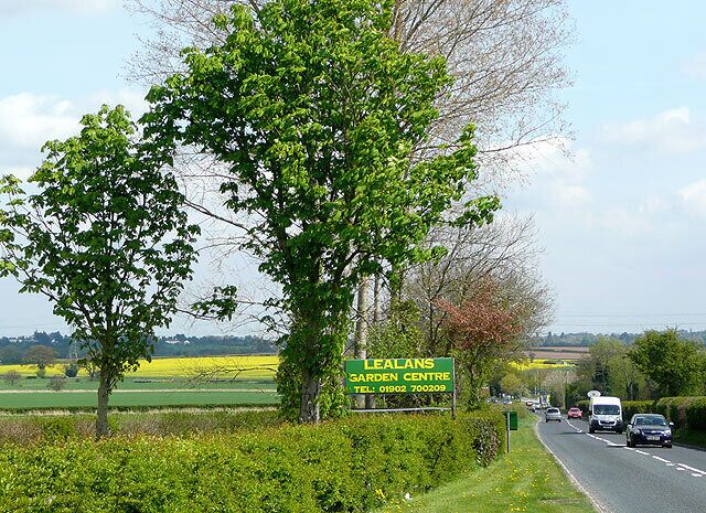 The A454 Bridgnorth Road near Shipley, Shropshire Lealans Garden Centre is behind the camera; the Pavilion Garden Centre, with its cluster of smaller traders by it, is just visible in the distance on the right. Most of the land around is arable and used for cereals, rape or potatoes. The rest is grazed by sheep and cattle.