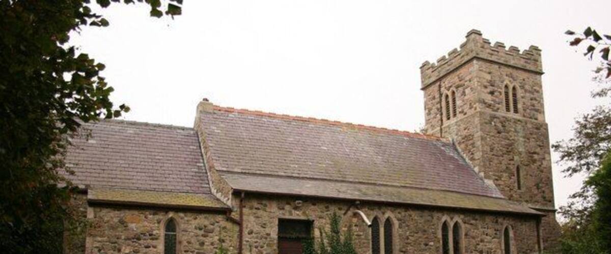 A stone church with a tower and arched windows.