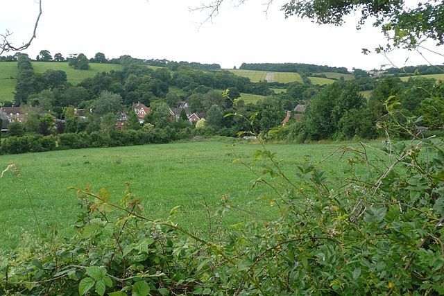 View across Swampton From a minor road in the north-east corner of the square showing the village in its setting in the valley of the Bourne Rivulet.