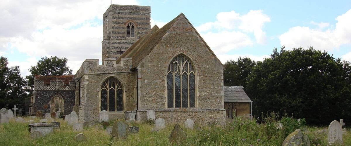 An old church with a tower and arched windows, surrounded by a graveyard with headstones.