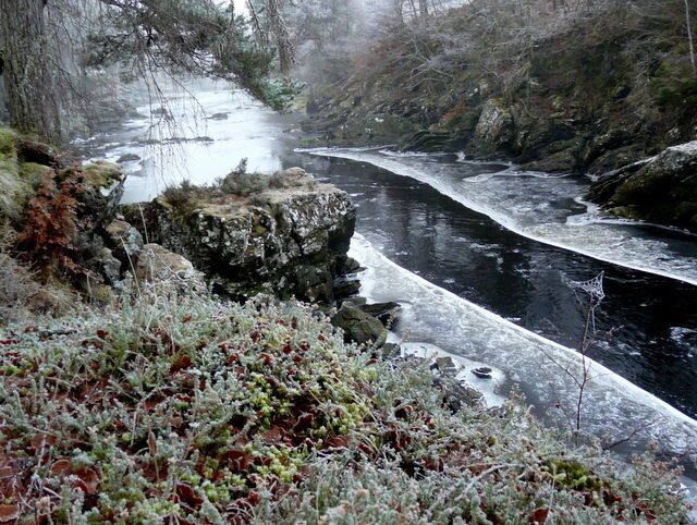 Un río serpentea a través de un paisaje rocoso con vegetación cubierta de escarcha.