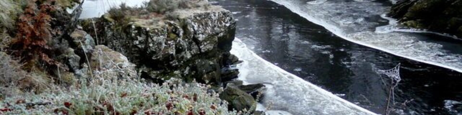 Un río serpentea a través de un paisaje rocoso con vegetación cubierta de escarcha.