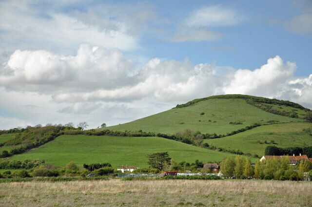 Rolling green hills, a clear sky, and a few buildings in the foreground.