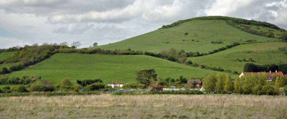 Rolling green hills, a clear sky, and a few buildings in the foreground.