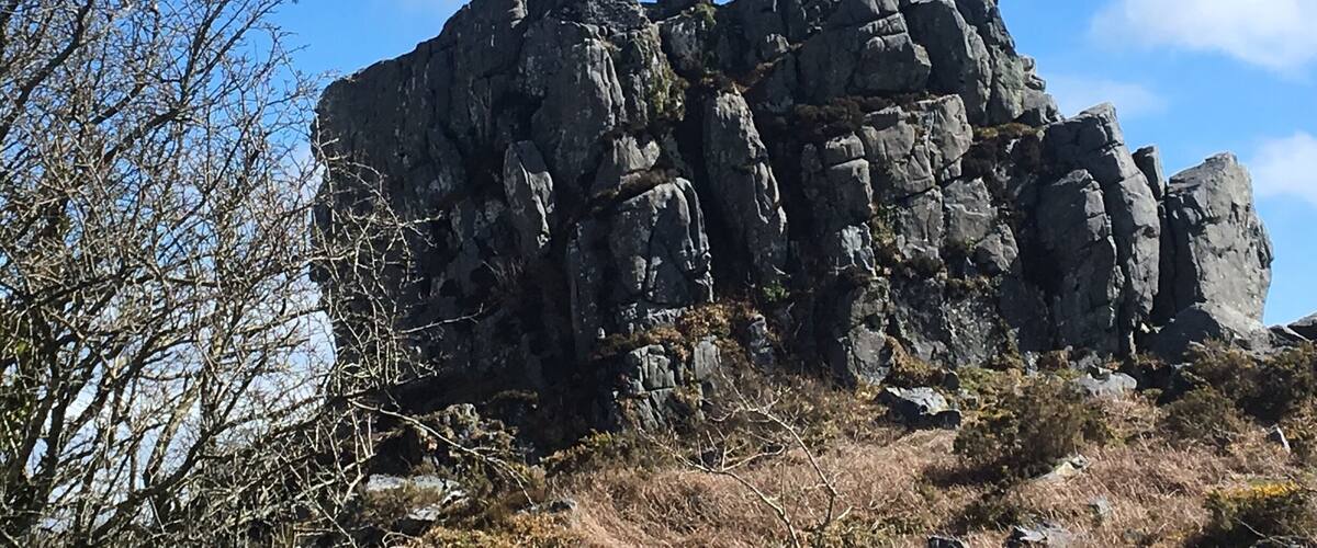 A rugged mountain with a prominent rock formation featuring an arch-like structure.