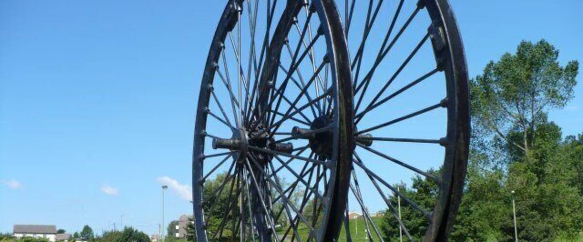 Colliery Wheels, Rhymney A plaque says "Erected by the Rhymney U D Council to mark the reclamation in 1970 of the old Maerdy Colliery and Rhymney Iron Works sites". The wheels came from a colliery at Abertysswg.