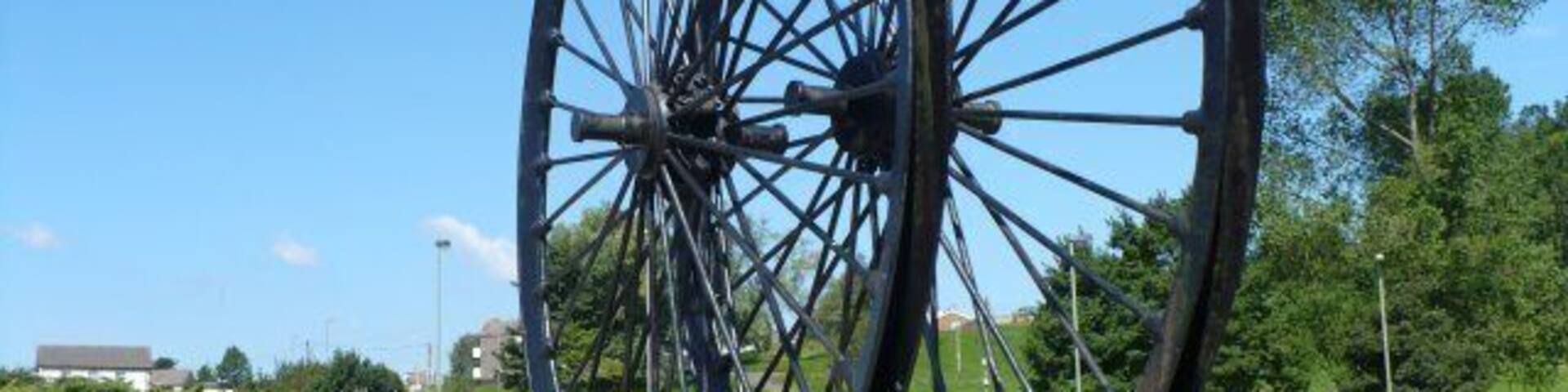 Colliery Wheels, Rhymney A plaque says "Erected by the Rhymney U D Council to mark the reclamation in 1970 of the old Maerdy Colliery and Rhymney Iron Works sites". The wheels came from a colliery at Abertysswg.