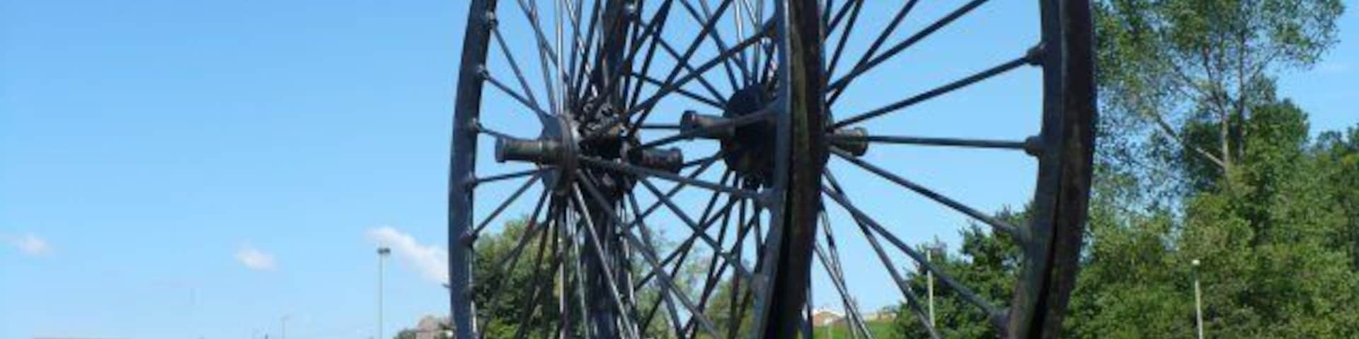 Colliery Wheels, Rhymney A plaque says "Erected by the Rhymney U D Council to mark the reclamation in 1970 of the old Maerdy Colliery and Rhymney Iron Works sites". The wheels came from a colliery at Abertysswg.