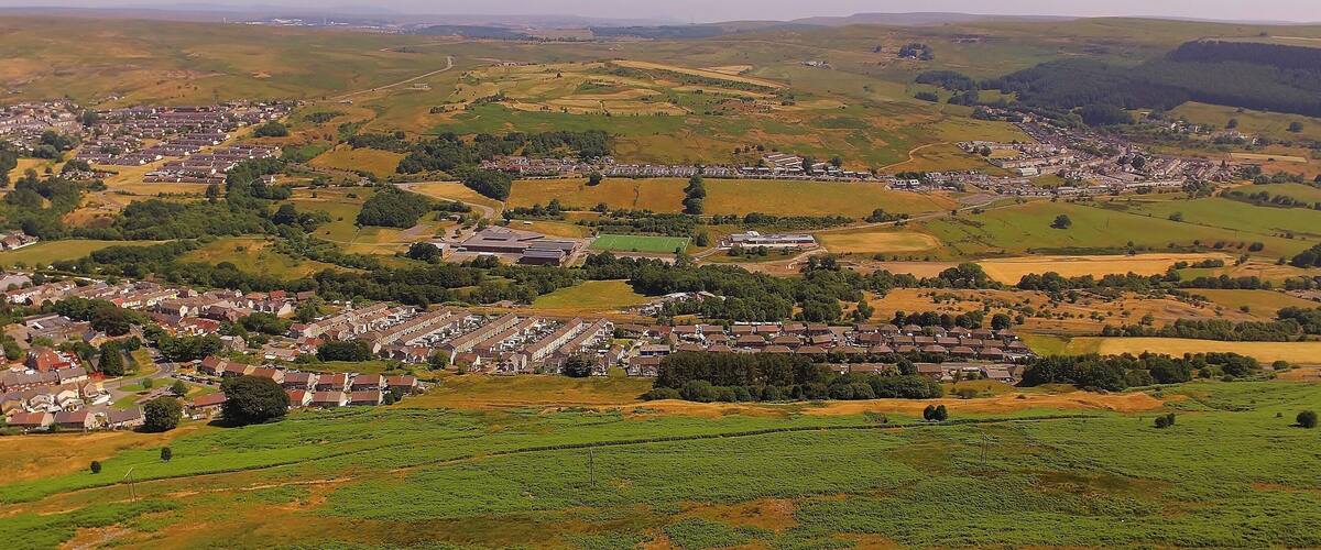 A rural landscape with a village, fields, and rolling hills.