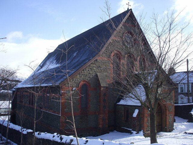 Una iglesia con techo empinado y paredes de ladrillo, rodeada de nieve.