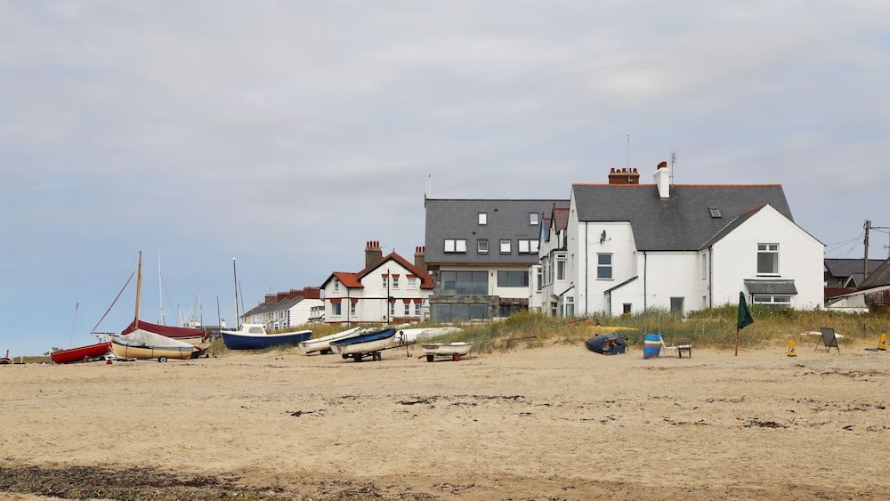 A sandy beach with several boats and a row of houses.