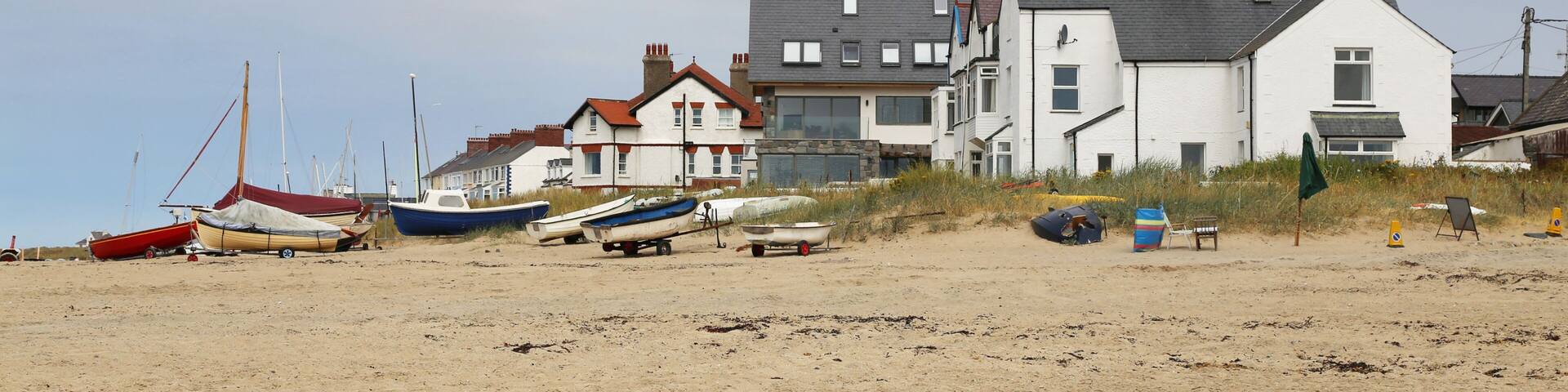 British beach side houses and boats on the sand at Rhosneigr, Isle of Anglesey, Wales, UK.