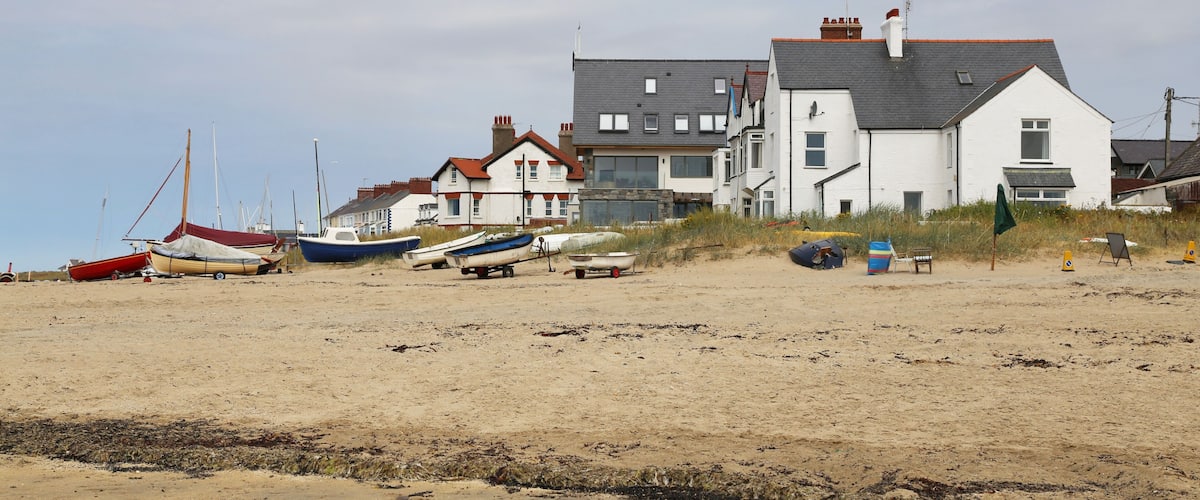 A sandy beach with several boats and a row of houses.