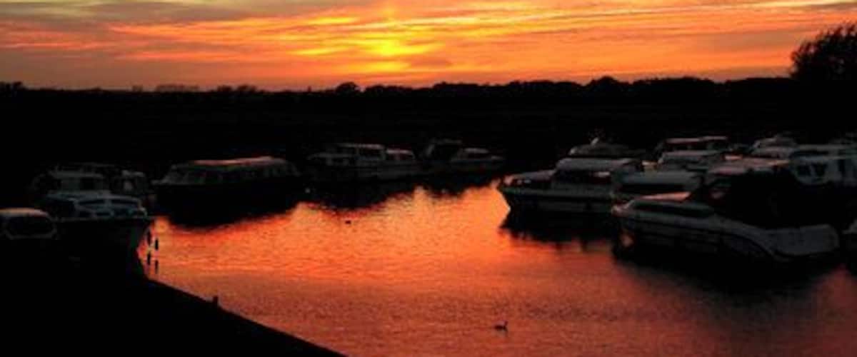 Sunset at Potter Heigham, Norfolk. The influence of the October sky enhances the natural beauty of Broadland. Here, the hire boats are moored for the night.